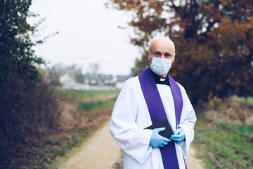 Man priest in a protective mask and protective gloves goes to pastoral visits