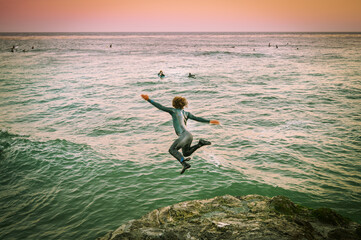 boy jumping off cliff into the ocean