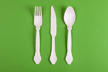 Wooden fork, knife and spoon on green background. Still life concept.