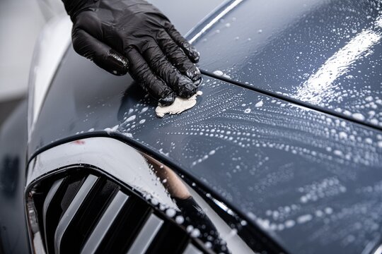 Man car wash worker cleaning car varnish with car clay.