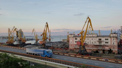 Fototapeta na wymiar Industrial port landscape with cargo cranes and cargo vehicle traffic by overpass