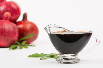 Grenadine in bottle and pomegranates on white background