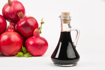 Grenadine in bottle and pomegranates on white background