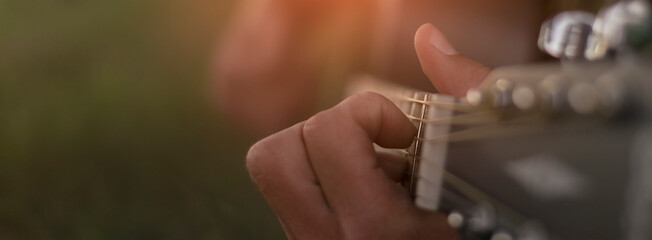 Musician playing guitar outdoors. Soft selective focus on fingers. Banner.