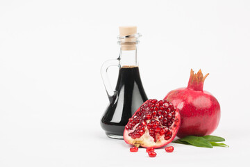 Grenadine in bottle and pomegranates on white background