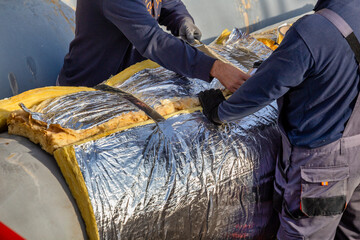 Workers laying insulated metal pipes for transporting hot water