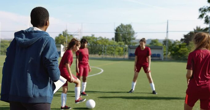 Female coach with soccer team during practice in soccer fied