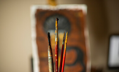 brushes in paint on the background of the painting on the easel in unfocused. background for...