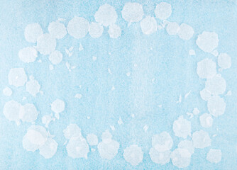 White round plastic foam sheet pieces on blue background. Winter snowfall concept. Frame of torn...