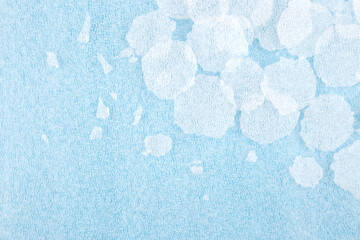 White round plastic foam sheet pieces on blue background. Winter snowfall concept. Torn foam...