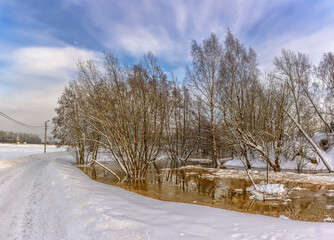 Fototapeta na wymiar The flood of the Korchminsky stream in the middle of winter in the village of Sapernoye.