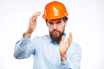 A man in a working uniform orange hard hat gestures with his hands emotions Construction engineer Professional