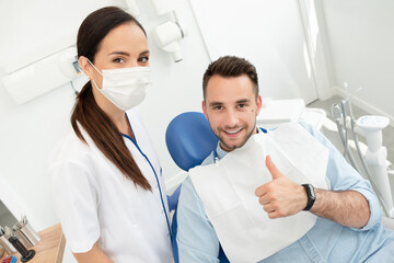 Young doctor dentist and patient showing thumb up