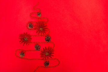 mock up of a garland of beads laid out in the form of a Christmas tree with decorations of cones of shiny red flowers.