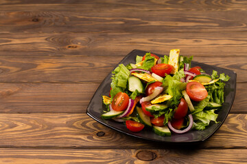 Traditional Arabic fattoush salad on a plate on a wooden background.