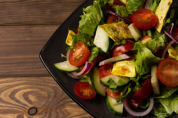 Traditional Arabic fattoush salad on a plate on a wooden background.