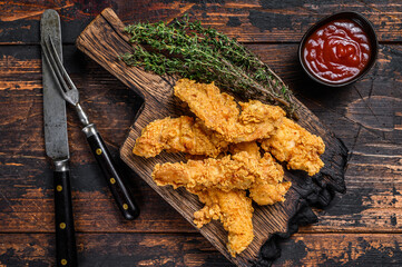 Chicken strips on a wooden cutting Board. Dark Wooden background. Top view