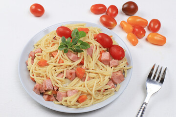 Italian spaghetti pasta with cherry tomatoes, tomato sauce, basil, fried carrots and sausage on a gray table, top view, selective focus