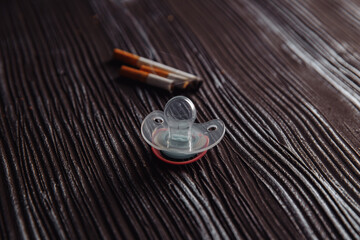 Cigarette and baby pacifier as a symbol of maternity and smoking.