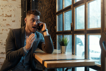 Surprised young businessman with mobile phone