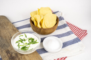 Chips in a wooden bowl with sour cream and green onion.