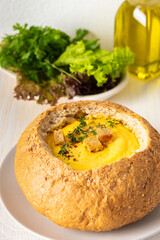 Pumpkin puree soup in a plate of bread, pumpkin soup with thyme , cheese and croutons on a white wooden background