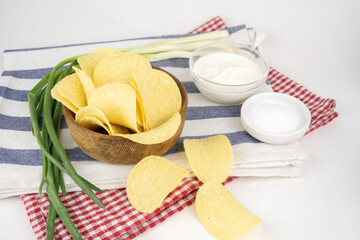 Chips in a wooden bowl with sour cream and green onion.