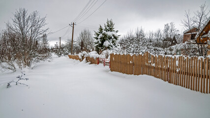 Real, Russian winter, when it is freezing and a lot of snow, in the country village, with small houses, roads through high snowdrifts and fences, drowned in the snow