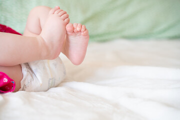 tiny, cute, bare feet of a little caucasian baby girl or boy on a white soft and cosy background, with pink skin, playfully wriggling its toes in excitement  