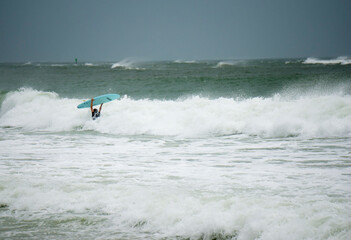 A surfer braves the high surf during tropical storm ETA on St. Pete Beach, Florida