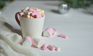 Cup with marshmallows on a white table. Christmas balls are blurred.