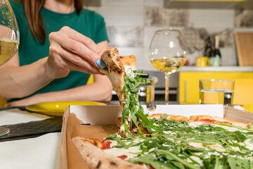 Womans hand takes a slice of Pizza. Italian pizza for dinner at home kitchen