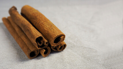 five brown cinnamon sticks lie against a gray linen cloth side view . Christmas symbols