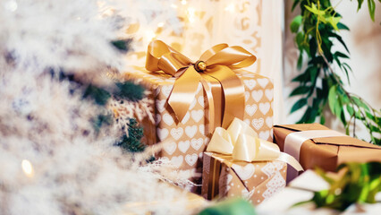 Holiday white gifts box with gold tape on background of Christmas tree bokeh, copy space