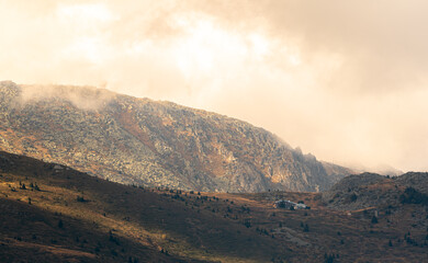 Autumn landscape in the mountains cloudy day sunrays wooden cottage on a ridge warm beautiful nature