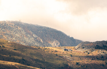 Autumn landscape in the mountains cloudy day sunrays wooden cottage on a ridge warm beautiful nature