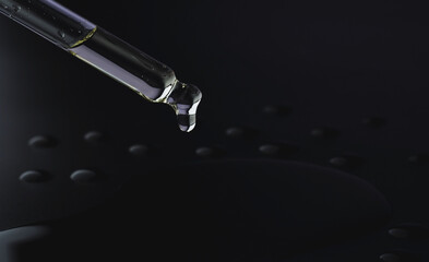 Oil dripping from a pipette on a black background