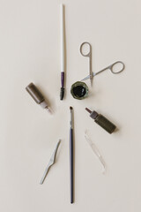 Eyebrow paint brushes, tweezers, scissors, eyebrow paint on a beige background. The concept of beauty, eyebrows.