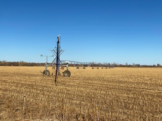 Commercial sprinkler on farmland with blue sky and field