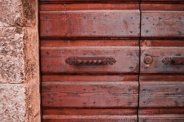 A brown wooden door with an iron handle (Gubbio, Umbria, Italy)
