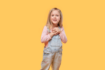 Beautiful cute blonde girl in casual clothes looks at the camera. Yellow isolated background.