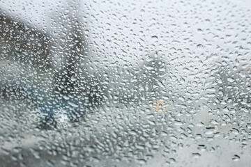 very poor view of the road, through a dirty windshield covered with ice, snow and water, against a blurred foreground and background with bokeh effect