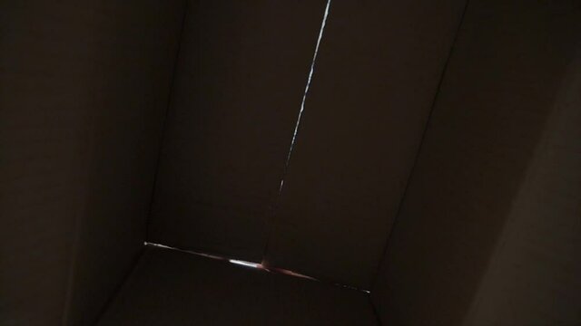 little boy opens a surprise parcel. kid a opens cardboard box lifestyle looking gift. child looks in the box is happy wonderment