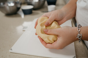 A close photo of the hands of a woman who is crushing shortbread dough in the kitchen