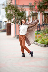 beautiful long-haired brunette in a light beige coat on the streets of the old city