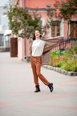 beautiful long-haired brunette in a light beige coat on the streets of the old city