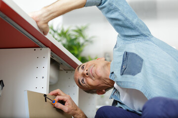 senior man assembling kitchen cupboard