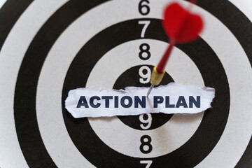 A piece of paper with the text is nailed to the target with a dart - ACTION PLAN