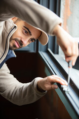 Naklejka premium construction worker repairing plastic window with screwdriver indoors