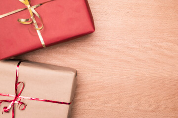 Flat lay photography of two wrapped gifts with craft paper with decorative ribbon on wood background with copy space for text.